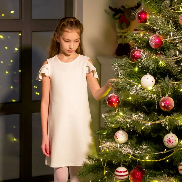 La niña decora un árbol de Navidad. Concepto de Año Nuevo, vacaciones familiares. —  Fotos de Stock