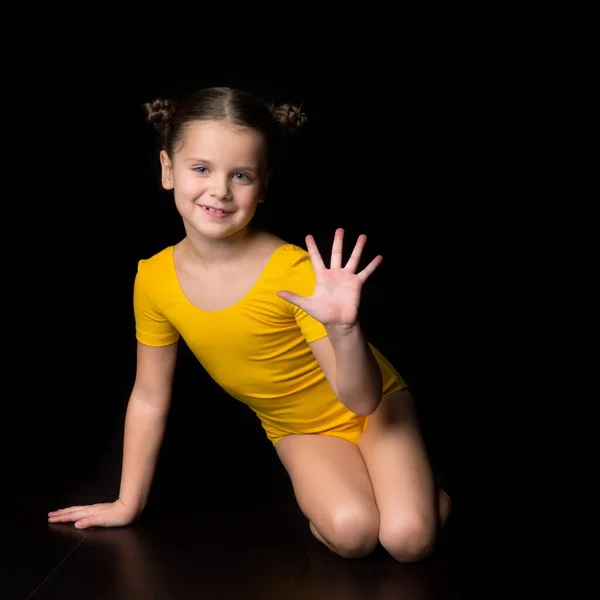 Linda niña alegre gimnasta sentada en el suelo —  Fotos de Stock