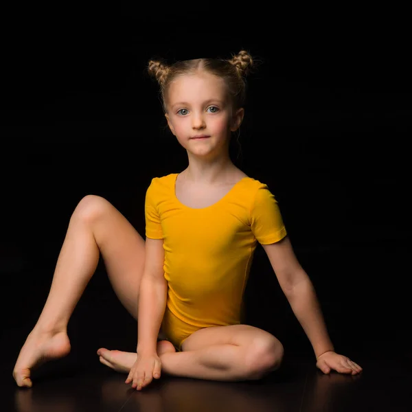 Vacker blåögd flicka gymnast i gul trikå Stockbild