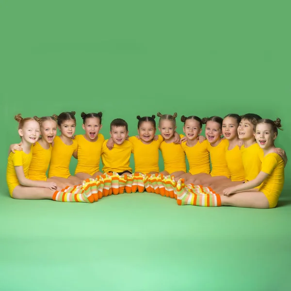 Petits enfants danseurs assis sur le sol en demi-cercle Photo De Stock