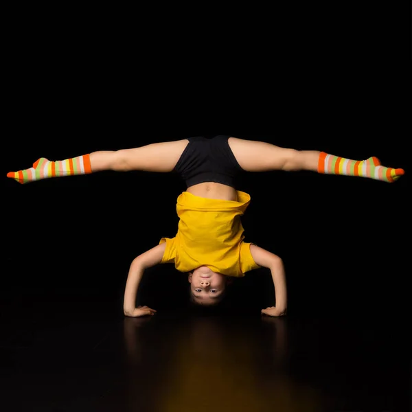 Ung pojke gör handstand och delar akrobatiska element. Stockfoto