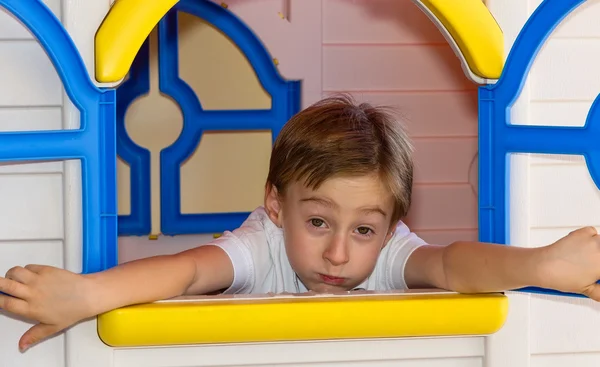 Cute child having a bored expression in toy house — Stock Photo, Image