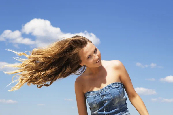 Young girl shaking her head over blue sky background — Stock Photo, Image