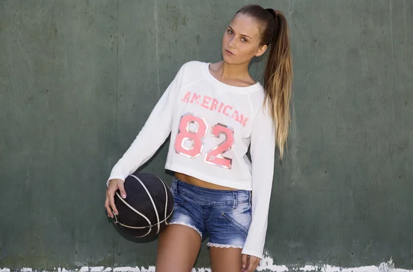 Girl holding basketball ball at wall — Stock Photo, Image