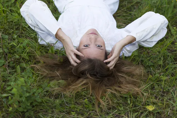 Menina bonita em vestido branco deitado na grama — Fotografia de Stock