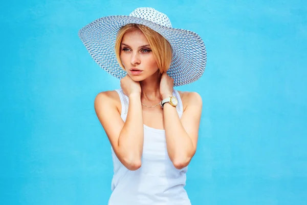 时尚的女孩，戴着帽子在她的头在蓝色背景上的肖像 — 图库照片