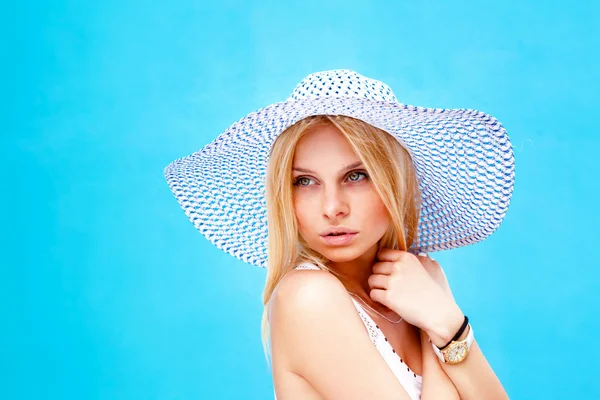 Egy kalap a fején, kék háttér felett divatos lány portréja — Stock Fotó