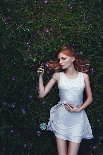 Fabulous portrait woman lying down in field with flowers — Stock Photo, Image