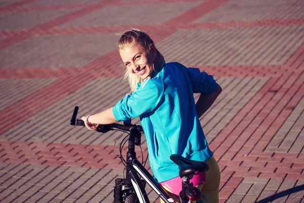 Chica con la bicicleta sonriendo y mirando en la cámara —  Fotos de Stock