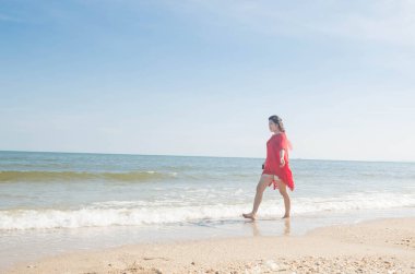 Kumsalda yürüyen bir kadın.