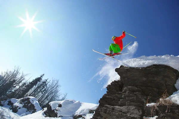 Skier стрибає проти блакитного неба зі скелі — стокове фото