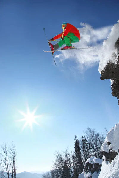 Skifahrer springt gegen blauen Himmel vom Felsen — Stockfoto