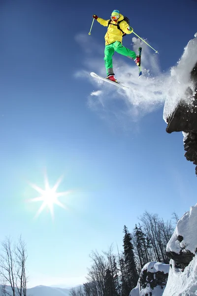 Skier стрибає проти блакитного неба зі скелі — стокове фото