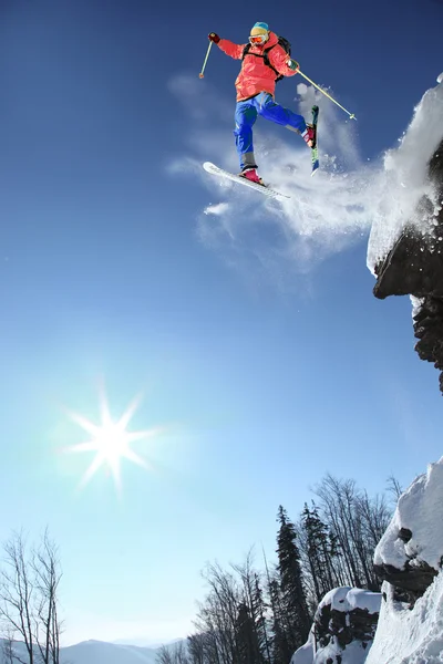 Skifahrer springt gegen blauen Himmel vom Felsen — Stockfoto