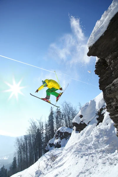 Skier стрибає проти блакитного неба зі скелі — стокове фото