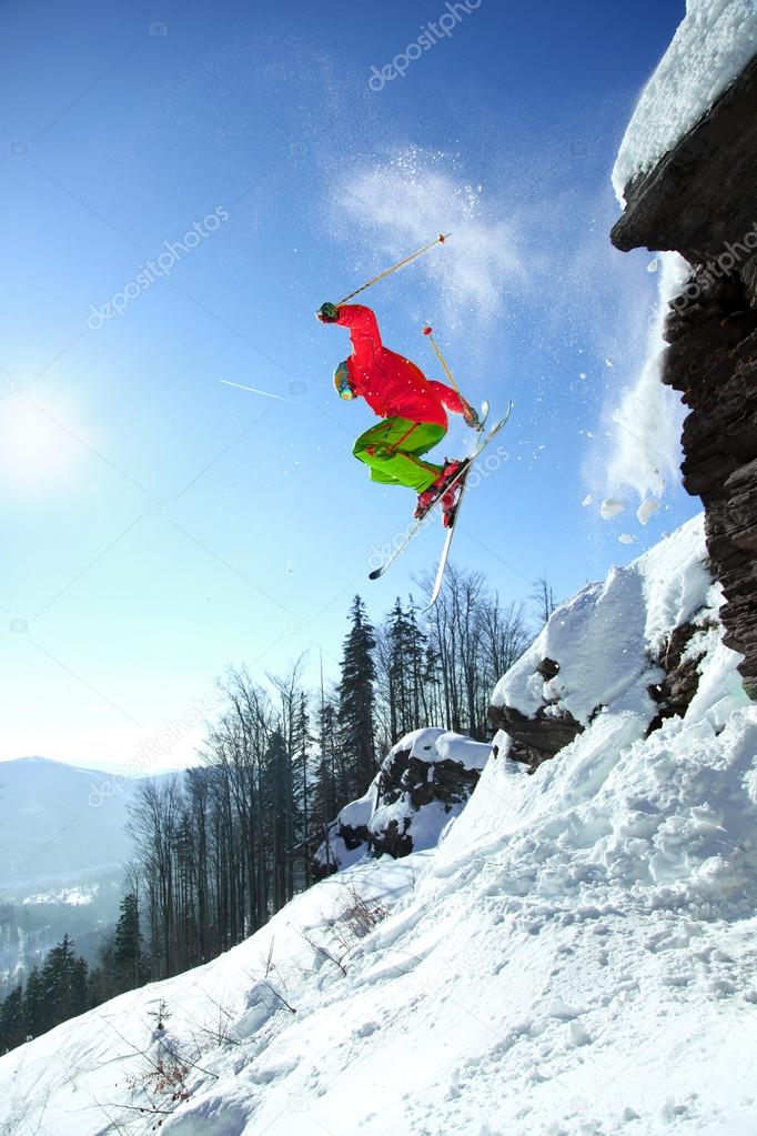 Skier jumping against blue sky from the rock