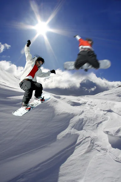 Snowboarders saltando contra el cielo azul — Foto de Stock