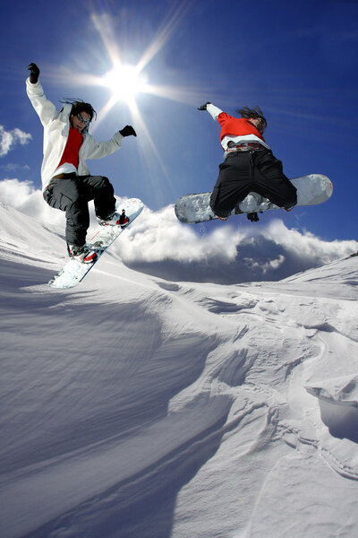 Snowboarders jumping against blue sky