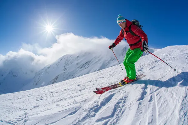 Narciarz narty zjazdowe w wysokich górach w słoneczny dzień — Zdjęcie stockowe