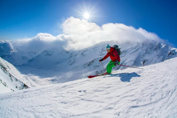 Yokuş aşağı güneşli gün boyunca yüksek dağlarda kayak kayakçı — Stok fotoğraf