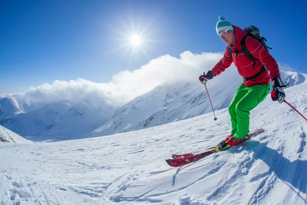Skier skiing downhill in high mountains during sunny day — Stock Photo, Image