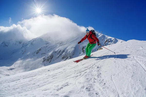 Skidåkare skidåkning slalom i höga berg under solig dag — Stockfoto