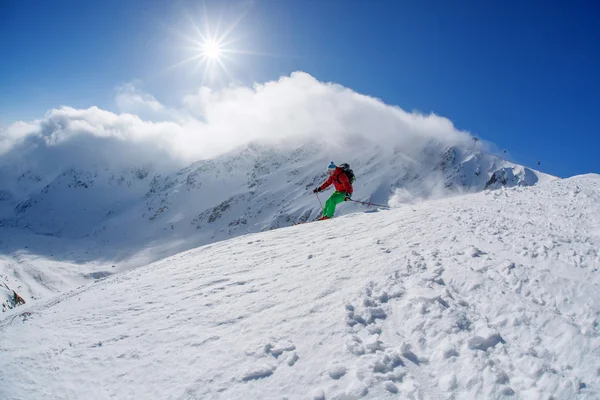 Skiër skiën afdaling in hoge bergen tijdens zonnige dag — Stockfoto