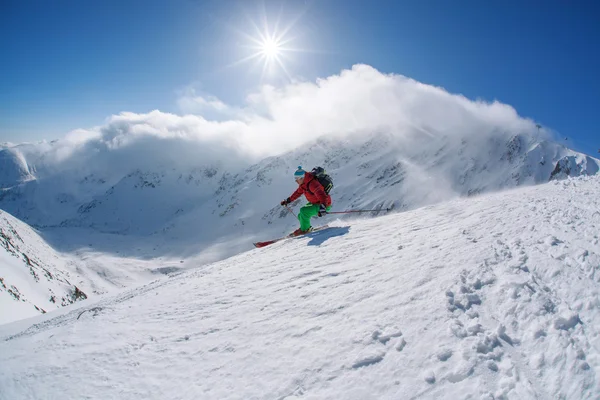 Skiër skiën afdaling in hoge bergen tijdens zonnige dag — Stockfoto