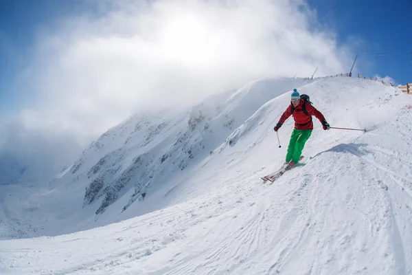 Skidåkare skidåkning slalom i höga berg under solig dag — Stockfoto