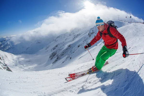 Narciarz narty zjazdowe w wysokich górach w słoneczny dzień — Zdjęcie stockowe