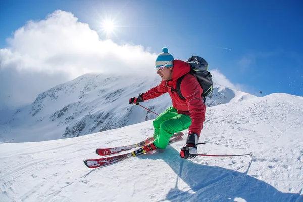 Esquiador esquiando cuesta abajo en las altas montañas durante el día soleado — Foto de Stock