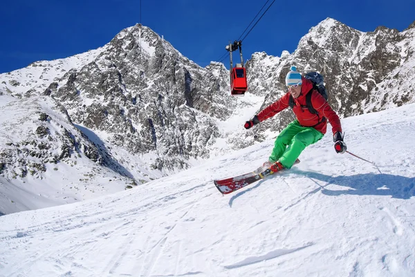 Esquiador esquiando cuesta abajo en las altas montañas durante el día soleado —  Fotos de Stock