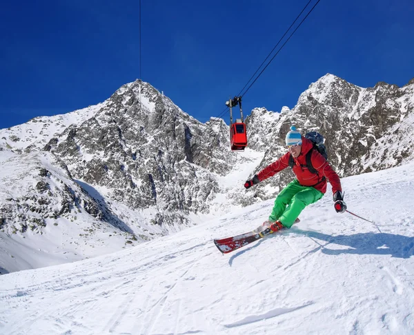 Skiër skiën afdaling in hoge bergen tijdens zonnige dag — Stockfoto