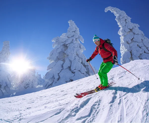 Esquiador esquiando cuesta abajo en las altas montañas durante el día soleado —  Fotos de Stock