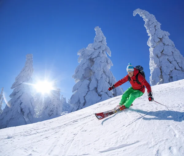 Skier skiing downhill in high mountains during sunny day Stock Photo