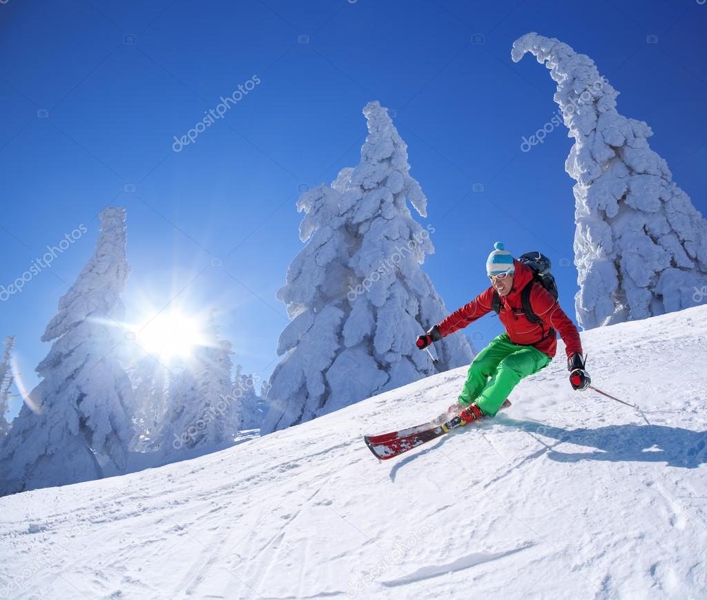 Skier skiing downhill in high mountains during sunny day