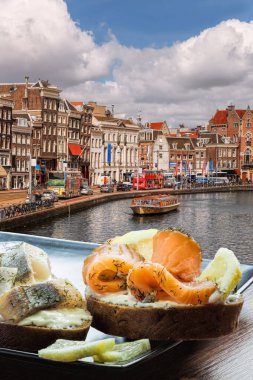 Hollanda kanalında turnuva teknesine karşı balık tabağı (salomon ve morina sandviçi) olan Amsterdam şehri