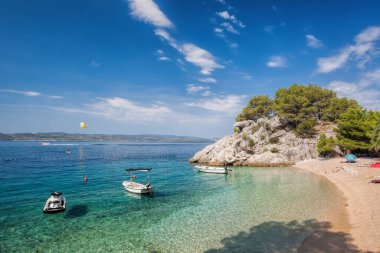 Amazing beach with boats against azure sea in Brela, Makarska, Dalmatia, Croatian coast clipart