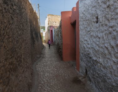 Young boy running as he is late for school in narrow alleyway of ancient city of Jugol. clipart