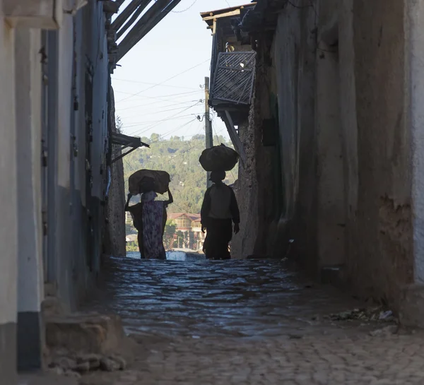 Las mujeres llevan cosas en sus cabezas en callejones estrechos de la antigua ciudad de Jugol . — Foto de Stock