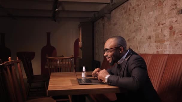 아프리카 사업가가 화상 회의 전화로 가상 팀 미팅을 하고 있는 가운데 카페에서 일하는 노트북을 이용해 다양 한 동료들 과 원격 비디오 채팅을 하고 있다.. — 비디오