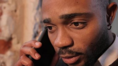 Gülümseyen genç melez iş adamı iş görüşmesi yapıyor ofiste telefonla konuşuyor, mutlu Afro-Amerikan pazarlamacısı. görünümü kapat