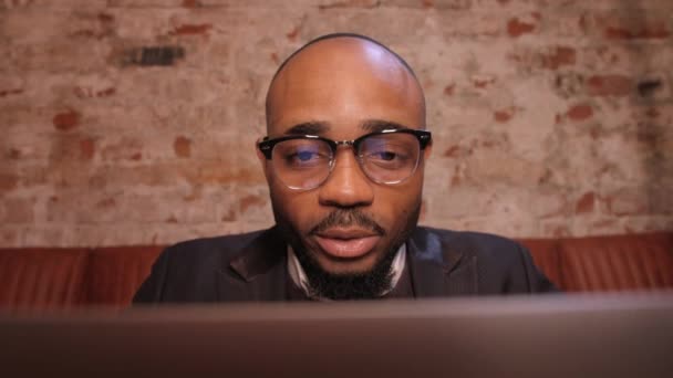 Homem de negócios africano tendo reunião de equipe virtual em videoconferência usando laptop trabalhando de café conversando com diversos colegas em videoconferência remota bate-papo online. — Vídeo de Stock