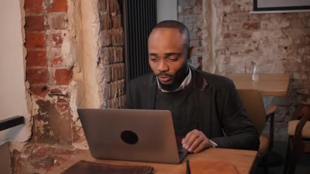 Az afro-amerikai egy laptopnak dolgozik, videokapcsolaton keresztül beszél. A fekete üzletember távolról dolgozik. Arc közel. — Stock videók