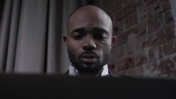 Afroameričan pracuje pro notebook, mluví přes video spojení. Černý obchodník pracuje na dálku. Obličej zblízka — Stock video