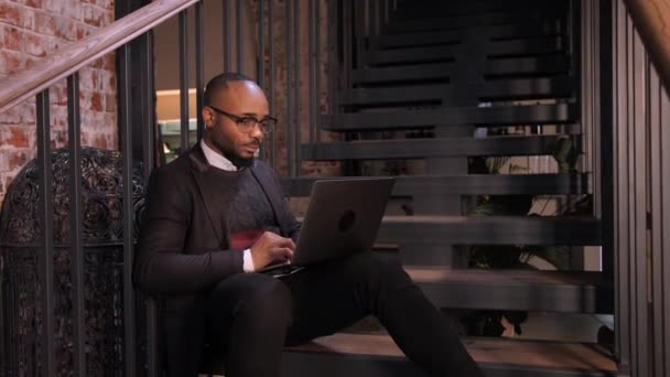 An African American student works at a laptop in a cafe — Stock Video