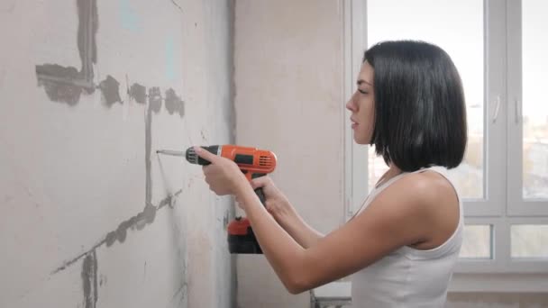 Beautiful girl in overalls with electric drill — Stock Video