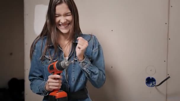 Uma mulher feliz faz reparos em casa. Uma mulher segura uma chave de fenda em suas mãos pela primeira vez e ri — Vídeo de Stock