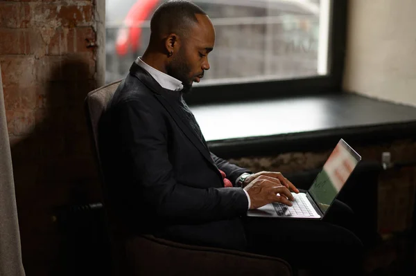 Um jovem aspirante a investidor afro-americano trabalha em um computador, analisa o mercado de valores mobiliários — Fotografia de Stock