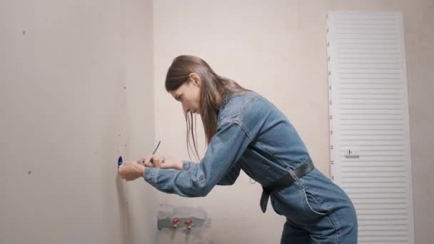 Renovatie appartement. Een mooie glimlachende vrouw repareert haar appartement. Lege muren, reparaties huis met eigen handen. — Stockvideo
